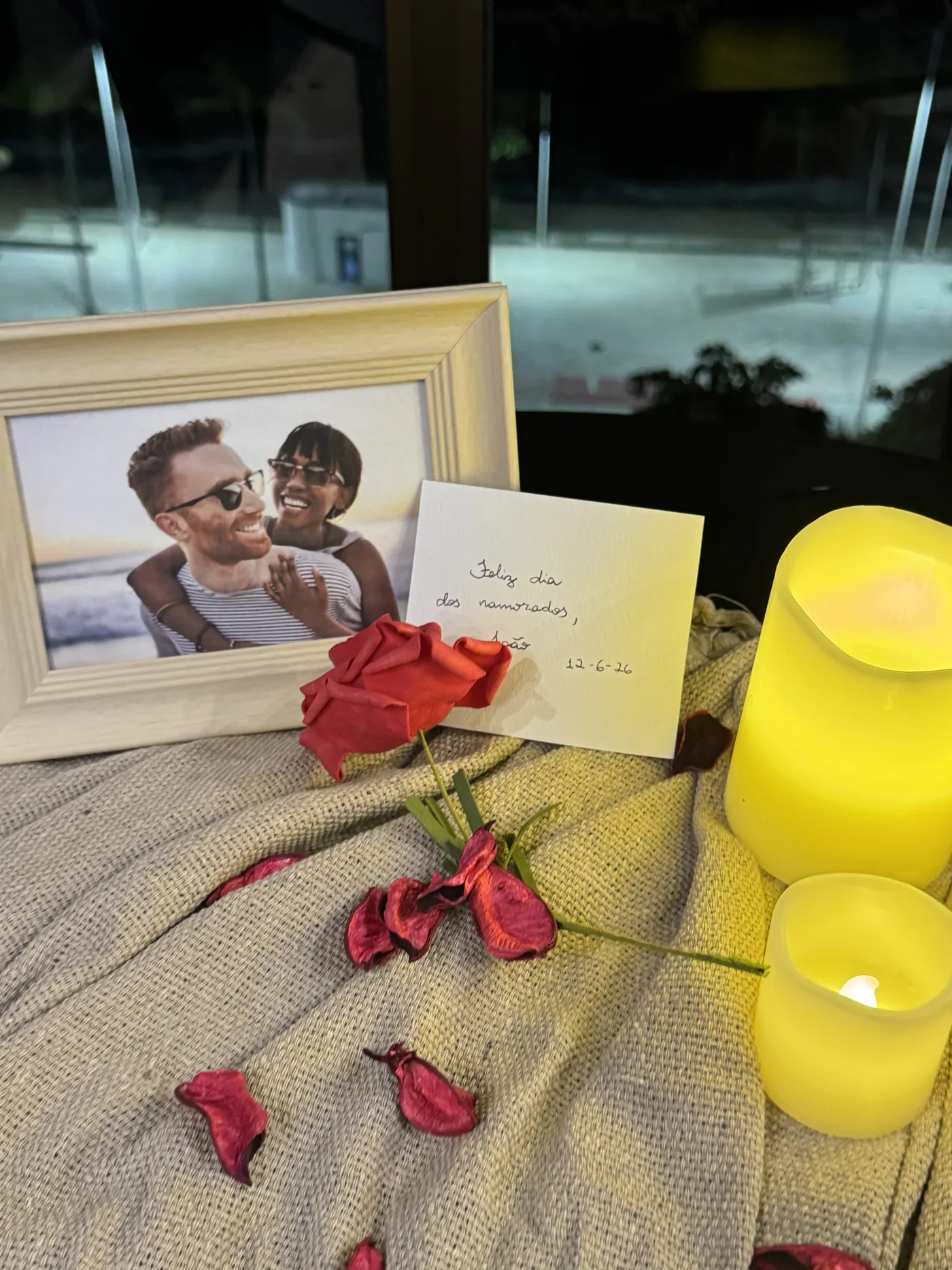 Ambientação romântica com velas, pétalas e porta-retrato